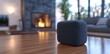 © Julia - A smart speaker is placed on a wooden table in a modern living room, where it sits beside a cozy fireplace that warms the space during the day