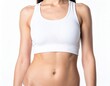 © Natty - A fit woman wearing a white sports bra and black shorts stands confidently in a sunlit park, showcasing her athletic physique and vibrant energy.