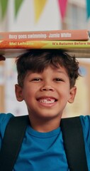 Leinwandbilder - Face, boy and books on head in classroom for education development, scholarship and ready for learning. Balance, child student and backpack with textbooks at school for language study and literature