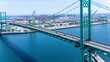 © Monet_P - High-angle view of the iconic Vincent Thomas Bridge spanning the Port of Long Beach in California. The turquoise suspension bridge crosses over calm blue water, with stacks of shipping container