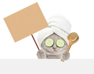 Fototapete - Cute kitten with towel on it head and with slices of cucumber on it eyes looks above blank white banner, holds shower brush and shows blank placard. isolated on white background