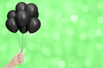 Aufkleber - Female hand holds bunch of black balloons on blurred green summer background. Empty space for text