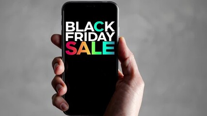 Poster - Shopper gripping smartphone showing vibrant black friday sale advertisement against neutral gray background, highlighting retail marketing and digital shopping trends