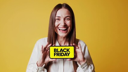 Poster - Young woman with long brown hair, wearing a white shirt, excitedly displays a smartphone with a vibrant yellow black friday message on the screen, set against a matching yellow backdrop