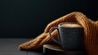 © GATE 22 - Close-up of a black mug with a handle, placed on a wooden surface. the mug is covered with a knitted orange blanket, which is draped over the side of the mug.