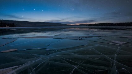 Poster - Frozen lake cracked into geometric ice patterns under twilight sky..

