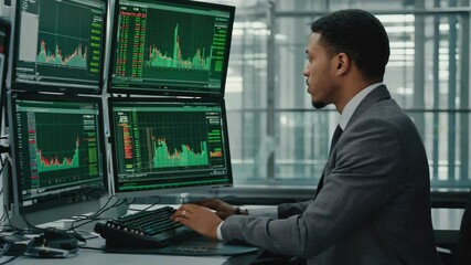 Poster - A businessman in a suit is analyzing financial data on multiple computer monitors in a modern office setting.