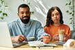 © LIGHTFIELD STUDIOS - Freelance African American couple collaborates on remote projects in cozy cafe setting