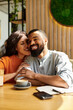© LIGHTFIELD STUDIOS - Couple enjoying a cozy moment together at a cafe, sharing laughter and love