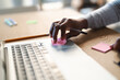 © Studio Marmellata - A young Arab man places a pink sticky note on his laptop. He is working at a desk with a pen, pencil, and other sticky notes nearby.  He is focused on his task.