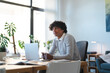 © Studio Marmellata - Young Arab man sits at his desk with a laptop. He is looking thoughtfully out the window in a bright, modern office space.