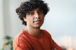 © Studio Marmellata - Portrait of a young Arab man with curly hair. He is wearing a casual orange shirt and looking directly at the camera.