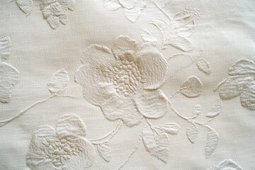 Poster - Close-up of off-white fabric with embossed floral embroidery, showing texture and detail.  Elegant and refined, ideal for textile or design background