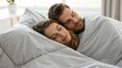 © Platon - Young adult man and woman sleeping soundly under a duvet, a tranquil moment showing deep sleep and shared relaxation.