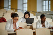 © Seventyfour - Diverse group of med students sitting in atrium of lecture hall and taking notes during class in college