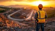 © irawan710 - Worker overseeing mining operation at sunset