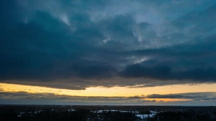 Wall Mural - Aerial sunset hyperlapse with snow clouds rolling in. Winter snowy weather in countryside. Drone timelapse of snow falling.