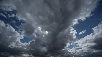 Wall Mural - Time lapse looking towards the sun of dramatic gray clouds moving through a dark blue summer sky. Isolated to sky only.
