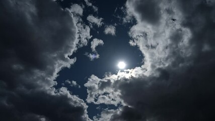 Wall Mural - Time lapse looking towards the sun of dramatic gray clouds moving through a dark blue summer sky. Isolated to sky only.
