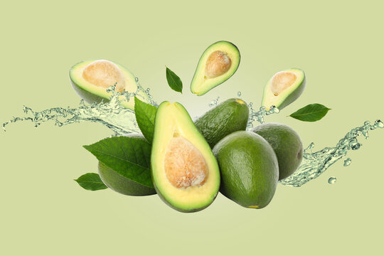 Healthy food, Avocados, leaves and water on light green background