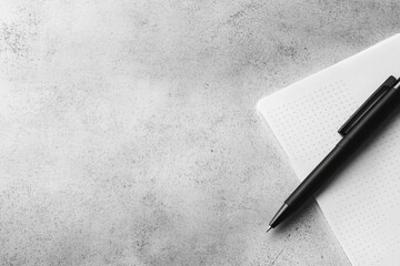 Poster - Clean white notepad with a dotted grid layout and a black pen resting diagonally on a smooth gray desk, providing ample space for notes and creativity