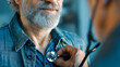 © Alex Alex - The doctor listens to the patient's heart using a stethoscope. A part of the doctor's face, his hands, a stethoscope and the patient's shirt are visible.