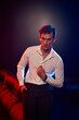 © LIGHTFIELD STUDIOS - Handsome young man exudes charm in stylish outfit under vibrant lighting during nighttime shoot
