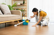 © Fahng - Woman is vacuuming her living room, reaching under the sofa to clean every corner