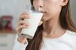 © Pormezz - Young Asian woman holding a glass of milk in the kitchen
