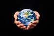 © Supriyono - Two hands gently cradle a small, detailed Earth globe against a stark black background