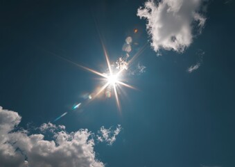 bright sun with lens flares and scattered clouds in a clear blue sky.