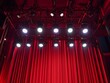 © Alexandr Efimov - The image depicts a stage with red curtains, featuring lighting equipment and microphones on stands. This suggests that the setting could be for a concert or a live performance event.