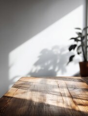 Poster - Rustic Wooden Table Surface with Play of Light and Shadow from Indoor Plant Against Neutral Wall Background for Product Display or Mockup