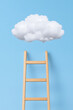 © photo for everything - A wooden ladder reaches toward a fluffy white cloud against a light blue background. Concept of aspiration, goals, and ambition.
