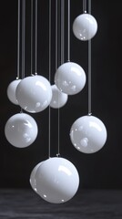Poster - Elegant arrangement of white glossy spheres suspended by thin cables against a dark background creating a modern and minimalist aesthetic with soft lighting and smooth texture