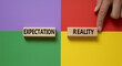 © mumtaz - Expectation versus reality concept with wooden blocks on a colorful background and a hand touching reality