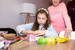 © Alvaro Lavin/Stocksy - Little Girl Opening Christmas Gifts with Her Mother Watching