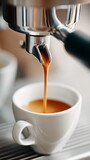 Espresso shot streaming from a coffee machine into a white ceramic cup, closeup view of fresh brewed coffee pour over, serving fresh coffee in a small cafe