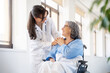 © Santi Nuñez/Stocksy - Young doctor comforting senior patient in wheelchair in hospital
