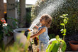 © Stephanie Tamir/Stocksy - Toddler laugh as she sprays herself with the water hose.