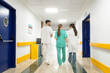 © Santi Nuñez/Stocksy - Medical team walking down hospital corridor, discussing patient care