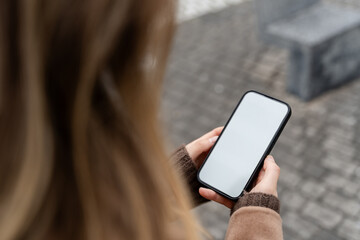 Woman using smartphone with blank white screen outdoors