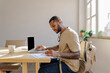 © BONNINSTUDIO/Stocksy - Focused man working on laptop and taking notes in modern office