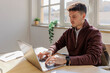 © BONNINSTUDIO/Stocksy - Focused office worker using laptop and drinking coffee at desk