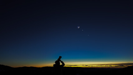Wall Mural - amateur astronomer looking at the evening skies, observing planets, stars, moon and other celestial 