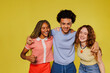 © BONNINSTUDIO/Stocksy - Three happy students embracing and smiling on yellow background
