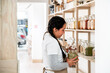 © David Prado/Stocksy - Woman Organizing Jars in Zero-Waste Store Interior