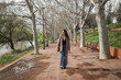 © Lupe Rodriguez/Stocksy - Woman walking along a tree-lined riverside path in the city