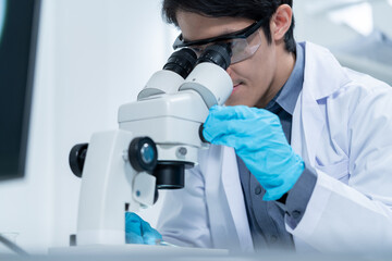 Wall Mural - asian researcher using a microscope in the clinical lab.male researcher working in the clinical labo