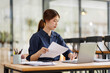 © David - Annual, summary report, laptop and paper placed at office desk. Asian woman work online and plan financial data with laptop, work in the office. Business woman and planner concept